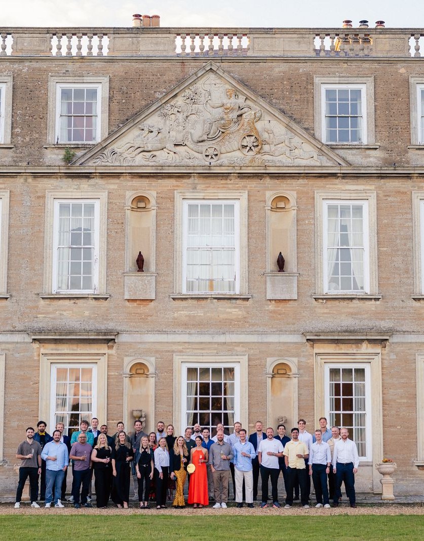 The whole company gathered on the gravel in front of the country house at golden hour